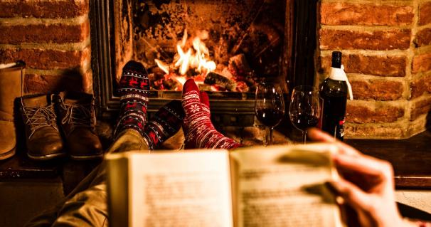 Couple with book resting by fireplace during Xmas