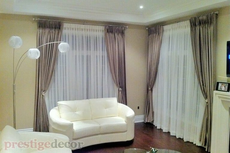 Stylish pinch pleat curtains in the living room with sheers, holdbacks and iron drapery hardware.
