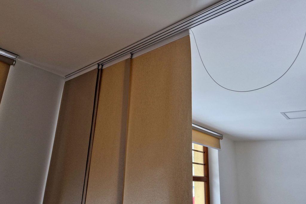 extendable hanging blind is a dividing partition made of textile beige blinds. home screen in the living room or dining room. rails and travel cable